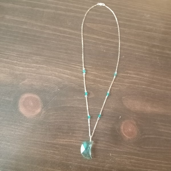 the lovely blue-green color of the moon pendant is created by treating clear quartz with vaporized metal, usually gold for this stone.